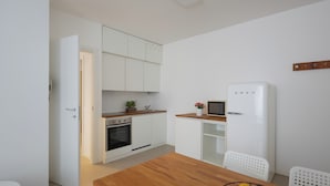A compact kitchen with white cabinets, a wooden countertop, a built-in oven, and a white refrigerator.
