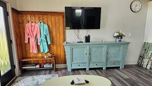 Una sala de estar con televisor, pared de paneles de madera, mueble azul turquesa y una mesa de centro.