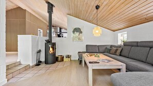 A modern living room with a wood-burning stove, a grey sofa, and a wooden coffee table. - Lovely home in Glesborg with sauna (Glesborg)