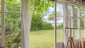 A conservatory with a view of a grassy garden and trees. - 2 bedroom cozy home in Faxe (Faxe)
