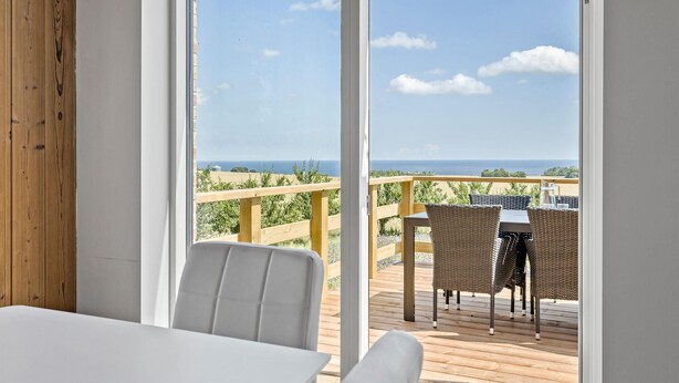 Un balcon avec des fauteuils en osier, une table et une vue sur la mer.
