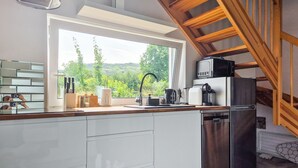 Una cocina moderna con un amplio ventanal, electrodomésticos de acero inoxidable y techo de madera.