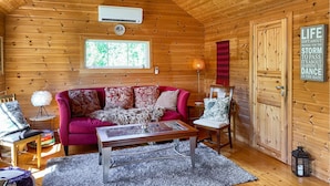 A cozy cabin interior with a wooden interior, a red sofa, a glass-top coffee table, and a large window. - 2 bedroom pet friendly home in Haddal (Haddal)