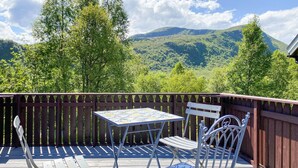 A wooden deck with a table and chairs, overlooking a mountainous landscape. - 2 bedroom pet friendly home in Haddal (Haddal)
