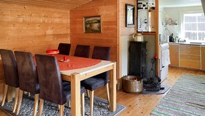 A cozy wooden cabin interior with a dining area featuring a table and chairs, a kitchen with a stove, and a view of the outside. - 2 bedroom pet friendly home in Haddal (Haddal)