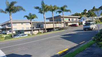 A multi-story motel with balconies, a parking area, and a clear blue sky.