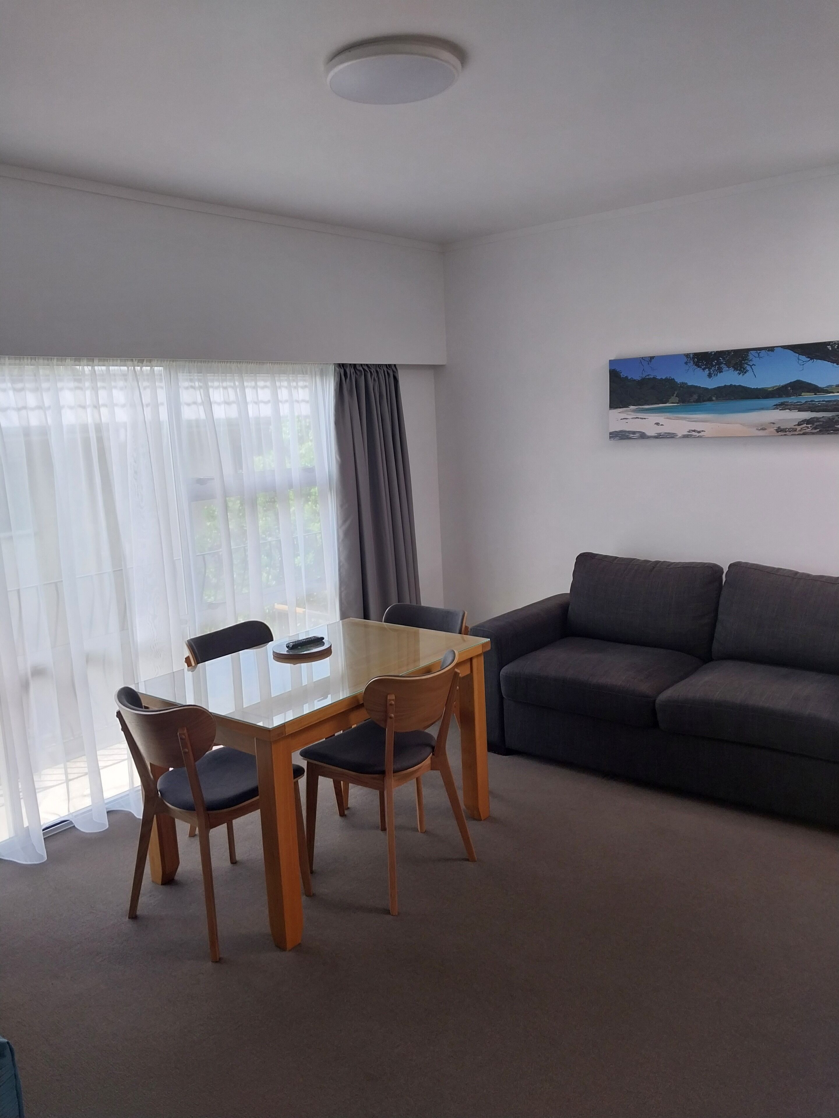 A modern living room with a dining table, chairs, a sofa, and a painting on the wall.