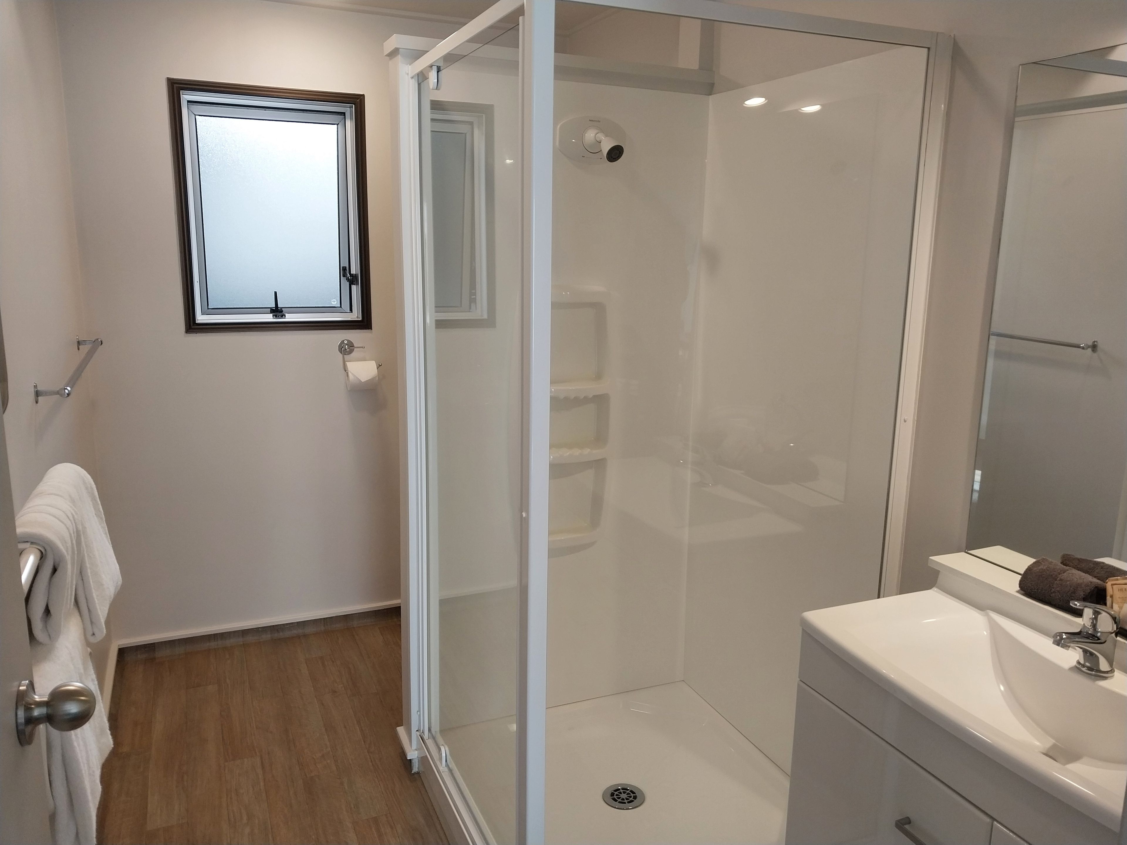 A modern bathroom with a glass-enclosed shower, a white sink, and a mirror.