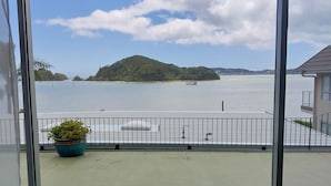 A balcony with a view of a calm body of water, a distant island, and a potted plant. - Bayview Motel (Paihia)