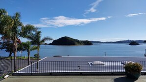 A rooftop terrace with a view of a calm lake, palm trees, and distant islands. - Bayview Motel (Paihia)