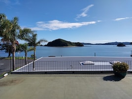 Una terraza en la azotea con vistas a un lago tranquilo, palmeras e islas a lo lejos.