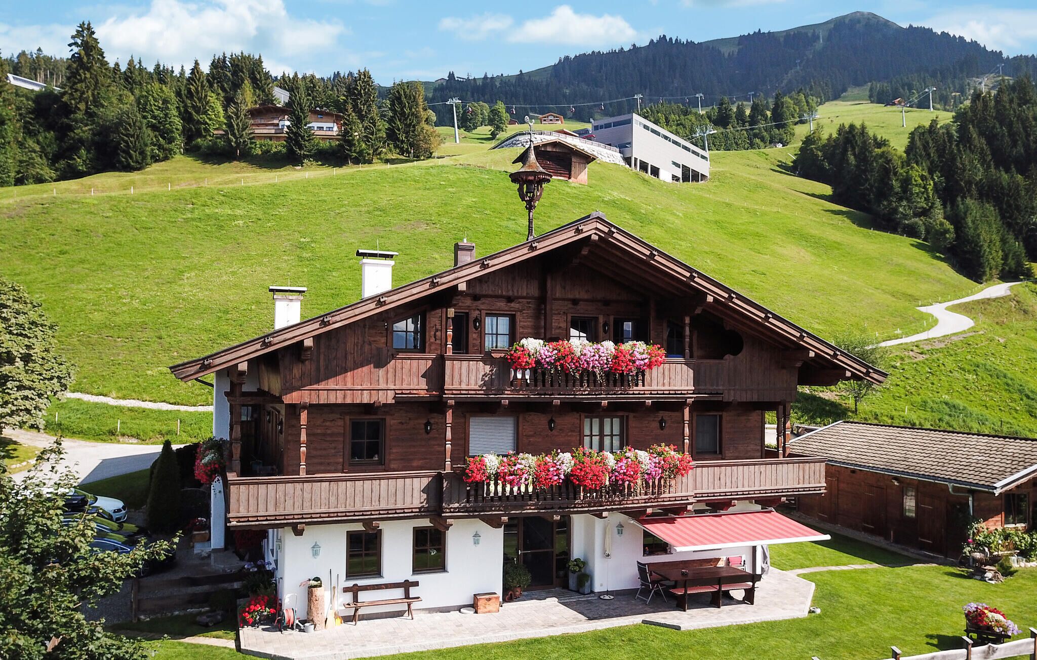 Eine Holzchalet mit Balkon, überdachter Terrasse und Blick auf eine Berglandschaft.