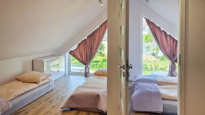 A bedroom with two beds, a window, and a view of greenery.