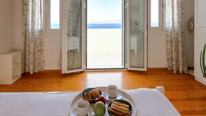 Une chambre avec balcon, un plateau de petit-déjeuner avec des croissants, une tasse et une pomme verte.