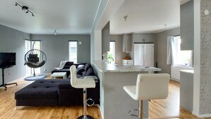 A modern living room with a black sectional sofa, a hanging chair, and a bar area with a white countertop. - Lovely home in Perstorp (Perstorp)