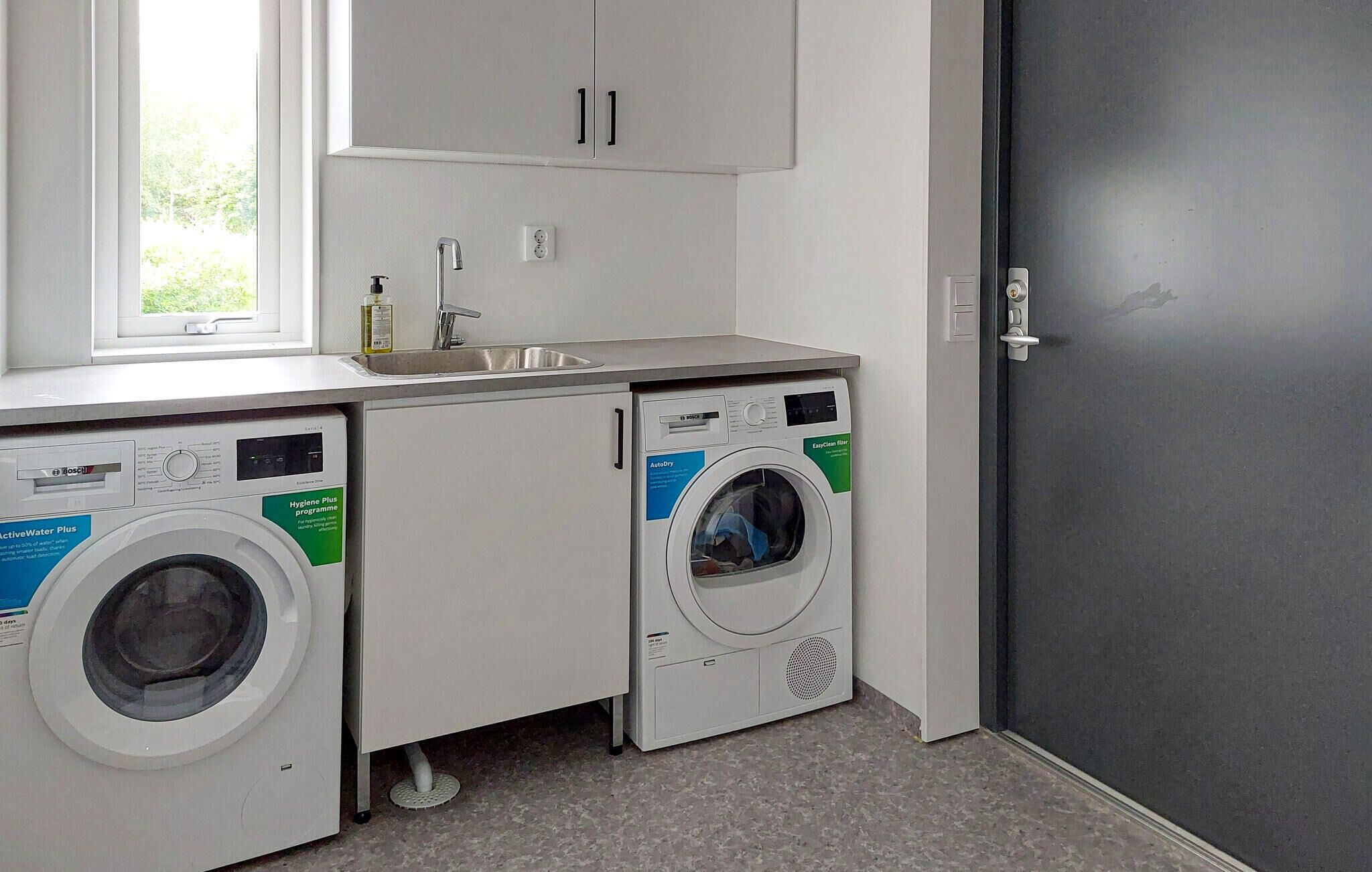 A laundry area with two front-loading washing machines, a sink, and a window.