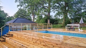 A wooden deck with a swimming pool, a wooden deck chair, and a small gazebo. - Lovely home in Perstorp (Perstorp)
