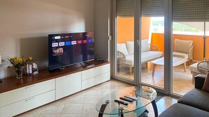 Un salon moderne avec un téléviseur à écran plat, une table basse en verre et un canapé.