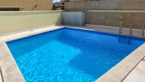 Une piscine rectangulaire à l’eau d’un bleu limpide, entourée d’une terrasse carrelée aux couleurs claires.