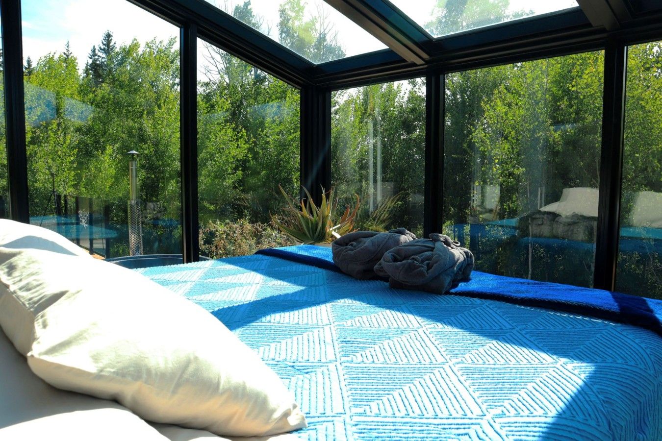 A bedroom with a large bed, a skylight, and a view of a forest.