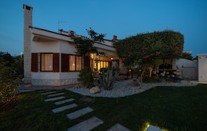 A modern house with a stone chimney, large windows, and a well-maintained garden with a cactus and flowering plants. - Nice home in Kozino with sauna (Kozino)