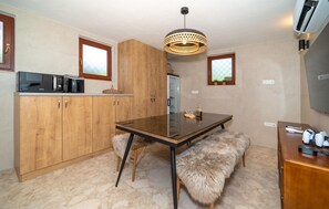 A compact kitchen with wooden cabinets, a microwave, a glass-top table, and a fur bench. - Nice home in Kozino with sauna (Kozino)
