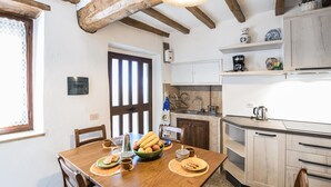 A kitchen with wooden cabinets, a dining table with chairs, and a window with blinds. - 2 bedroom pet friendly home in Todi (Todi)