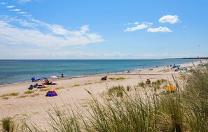A beach with tents and umbrellas, a sandy shore, and the ocean. - Awesome home in Væggerløse with sauna (Væggerløse)