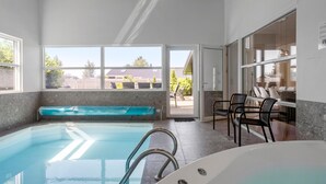 A modern indoor swimming pool with a clear view of the outside, a seating area with chairs, and a large window. - Awesome home in Væggerløse with sauna (Væggerløse)