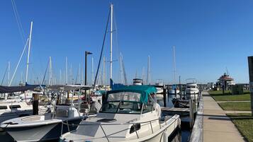 A marina with multiple boats docked along a concrete walkway.