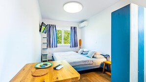 Habitación compacta con cama, una mesita, televisión y ventana con cortinas.