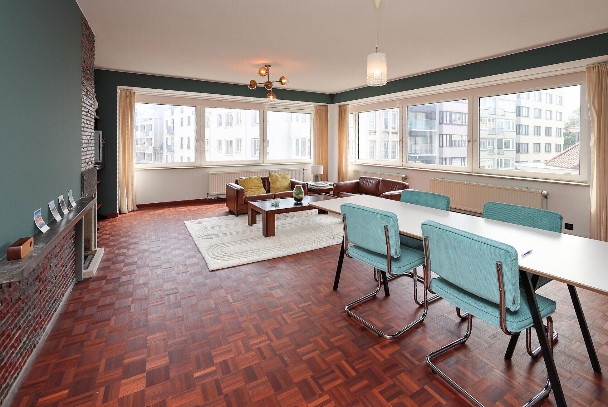 A spacious room with a large dining table, chairs, a sofa, and a fireplace.