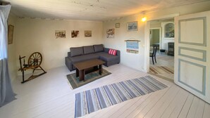 A living room with a grey sofa, a wooden coffee table, a patterned rug, and a spinning wheel. - 3 bedroom amazing home in Grundsund (Grundsund)
