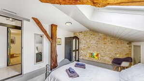 Ein Schlafzimmer mit einem großen Bett, einem Holzbalken, einer Steinwand und einem Fenster.