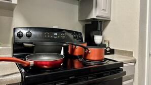 A kitchen with a black stove, two red pots, a coffee maker, and a Keurig coffee pod. - Worker friendly, cozy, great location, quiet, full kitchen, WiFi,  (Sherman)