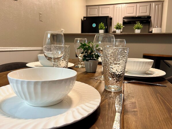 Une table à manger dressée avec des bols blancs, des assiettes et de la verrerie transparente.