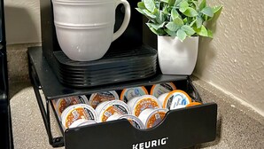 A Keurig coffee maker with a white cup and a potted plant beside it, and a Keurig branded coffee pod holder below. - Worker friendly, cozy, great location, quiet, full kitchen, WiFi,  (Sherman)