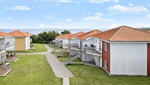 Una hilera de acogedoras cabañas frente a la playa, con mobiliario exterior y una vista despejada al mar.