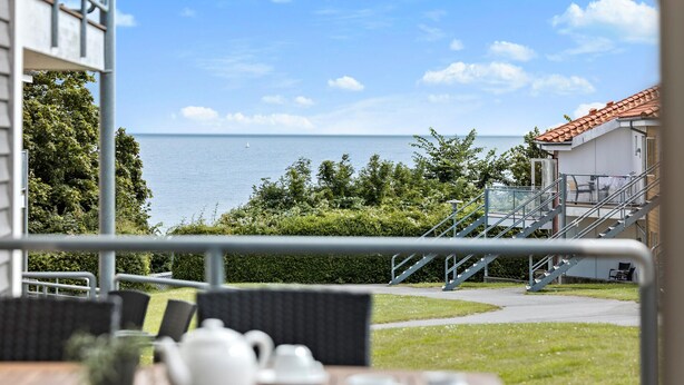 Una terraza con vistas al mar, mobiliario exterior y una escalera que lleva a un edificio.