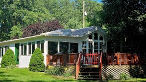 A house with a covered porch, a fenced deck, and a lawn.