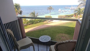 Un balcon avec vue sur l’océan, une petite table et deux chaises.