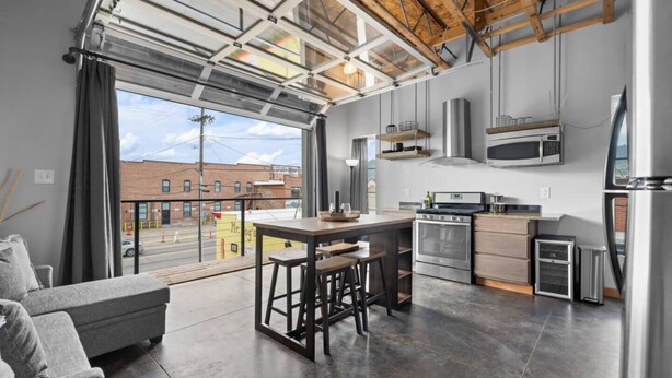 A modern kitchen with a large island, stainless steel appliances, and a view of the street.