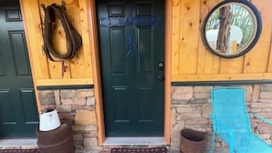 A wooden door with a metal gate, a blue metal chair, and a stone-paved entrance.