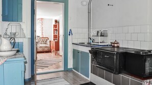 A kitchen with a stove, sink, and cabinets. There is a doorway leading to a living room with a sofa and a coffee table. - Cozy home in Kristinehamn with WiFi (Kristinehamn)