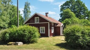 A red wooden house with a sloped roof, surrounded by lush greenery and trees. - Cozy home in Kristinehamn with WiFi (Kristinehamn)