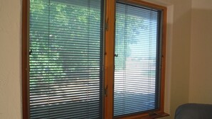 Una habitación con dos ventanas de madera y persianas horizontales.