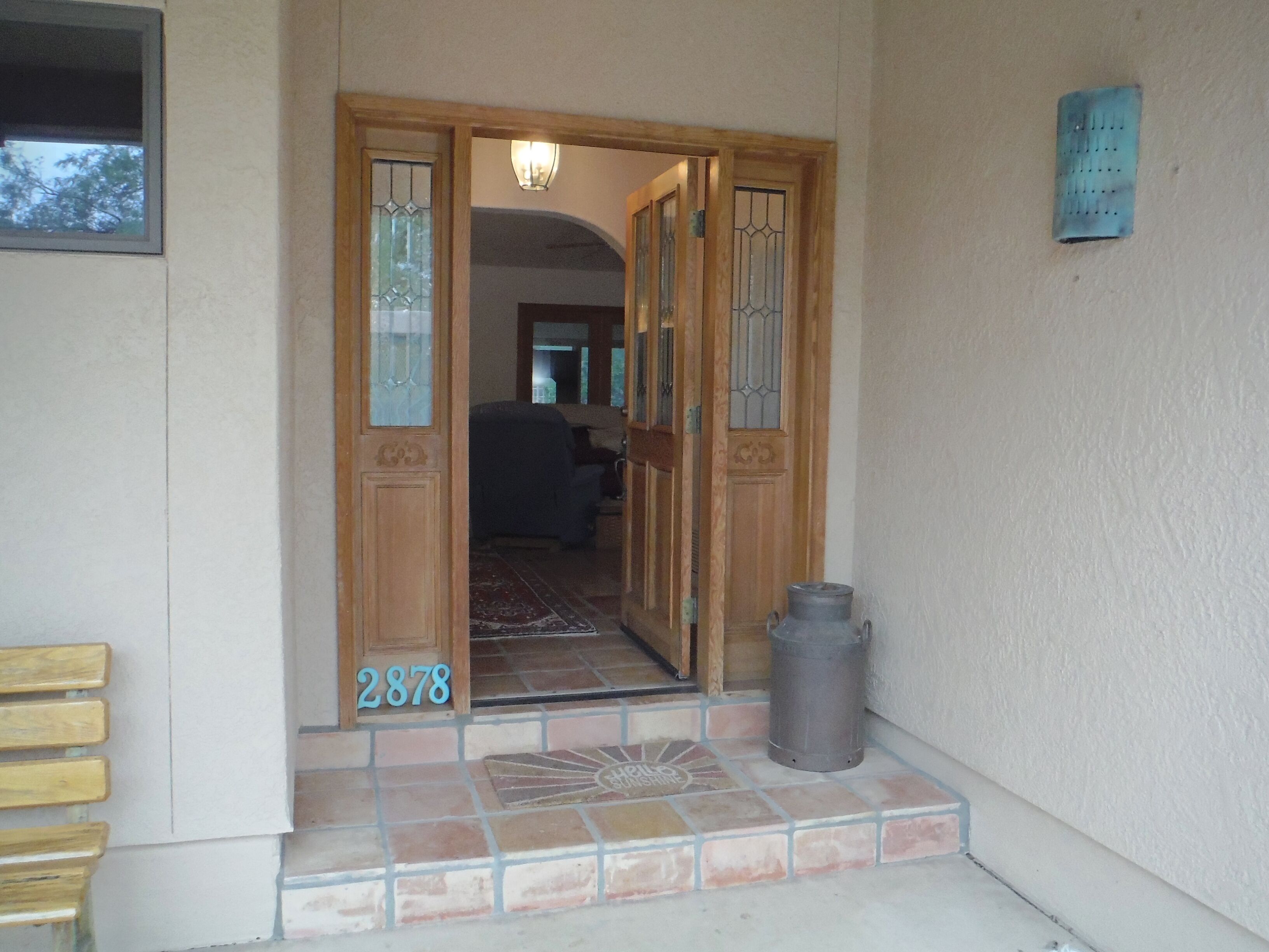 Una puerta de madera con paneles de vidrio y el número 2878 en el suelo.