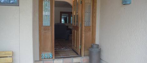 Una puerta de madera con paneles de vidrio y el número 2878 en el suelo.