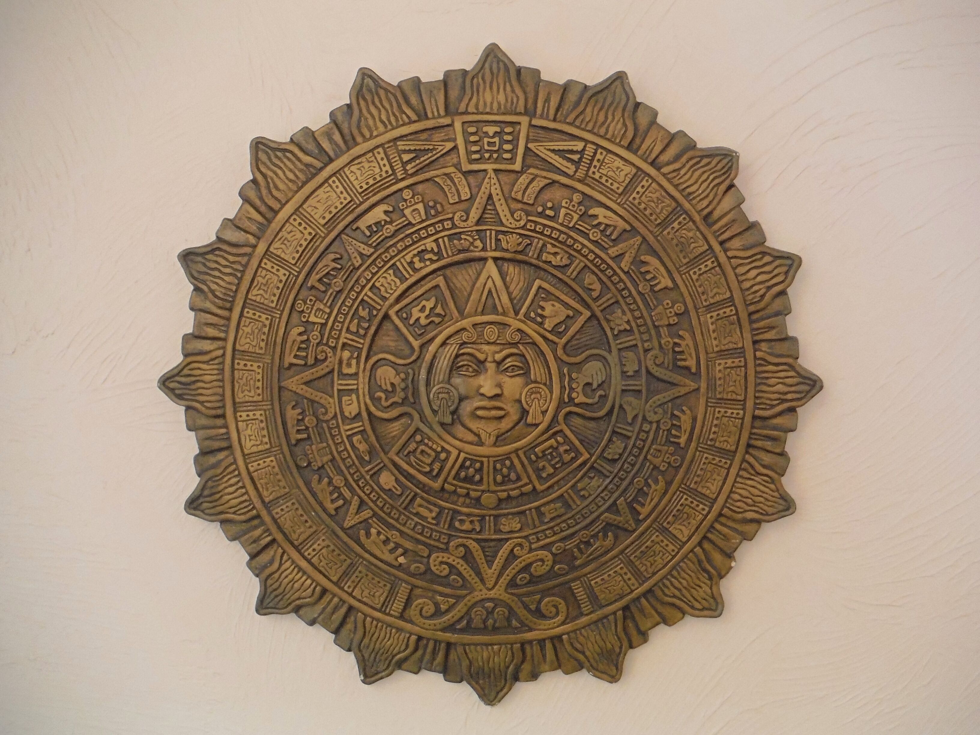 A circular wall decoration with intricate patterns and symbols, likely representing cultural or historical themes.