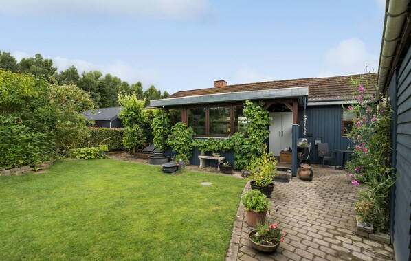 A backyard with a patio, a barbecue area, and various potted plants. - 2 bedroom nice home in Juelsminde (Juelsminde)